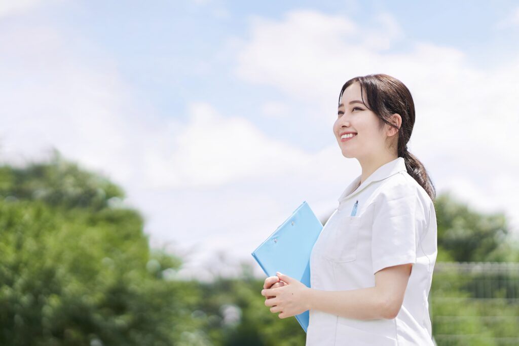 白衣の看護師が青いファイルを持っている様子。